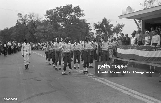 View of a group of young uniformed boys, performing a synchronized routine, while marching during the Bud Billiken Day parade, Chicago, Illinois, mid...