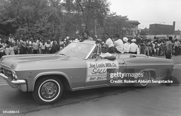 View of representatives of the Joe Louis Milk Company as they ride in an open covertible while participating during the Bud Billiken Day parade,...