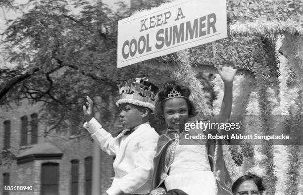 The king and queen of the Bud Billiken Day parade wave to the crowd while riding on a float during the parade, Chicago, Illinois, mid to late 1960s ....