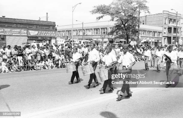 View of the uniformed drummers from a high school marching band, as they participate in the Bud Billiken Day parade, Chicago, Illinois, mid to late...