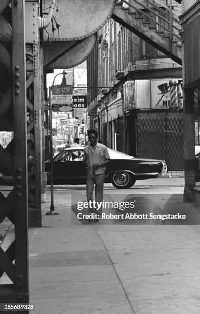 View of a man as he walks along a sidewalk, Chicago, Illinois, mid 1960s.