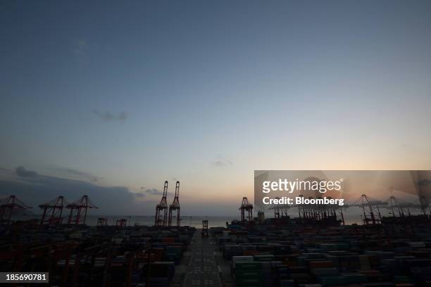 The sun set behind cranes and shipping containers stacked at the Yangshan Deep Water Port, part of China Pilot Free Trade Zone's Yangshan free trade...