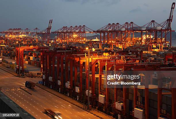 Trucks carrying containers drive through the Yangshan Deep Water Port, part of China Pilot Free Trade Zone's Yangshan free trade port area, at night...