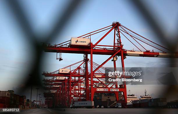 Vessel being loaded with shipping containers is seen through a fence at the Yangshan Deep Water Port, part of China Pilot Free Trade Zone's Yangshan...