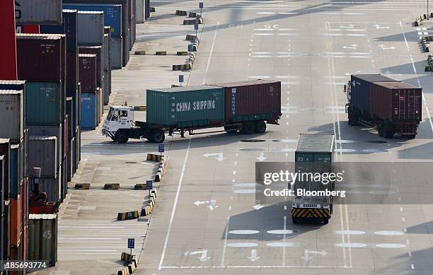 Trucks carrying shipping containers drive through the Yangshan Deep Water Port, part of China Pilot Free Trade Zone's Yangshan free trade port area,...