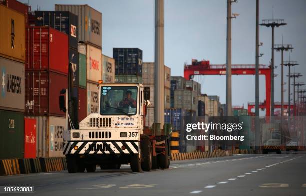 Trucks drive past shipping containers stacked at the Yangshan Deep Water Port, part of China Pilot Free Trade Zone's Yangshan free trade port area,...