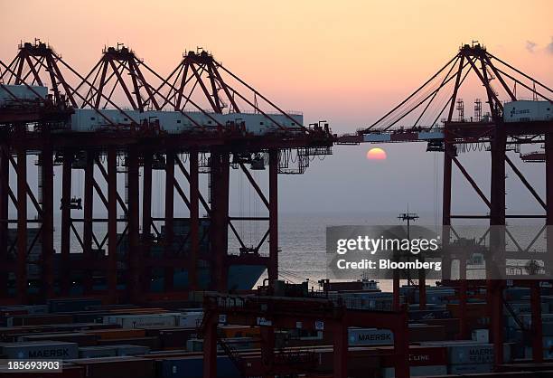 The sun sets behind cranes at the Yangshan Deep Water Port, part of China Pilot Free Trade Zone's Yangshan free trade port area, in Shanghai, China,...