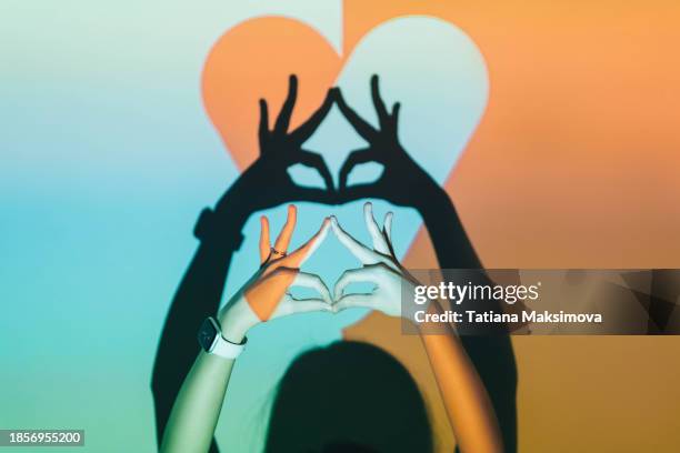 female hands show eyes on background of two-color heart, projection on wall. - superhero shadow stock pictures, royalty-free photos & images