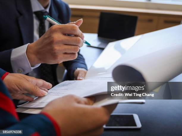 an asian male executive is holding a pen and signing a document held by an asian female secretary. only human hands are shown, no face. - paper furniture stock pictures, royalty-free photos & images