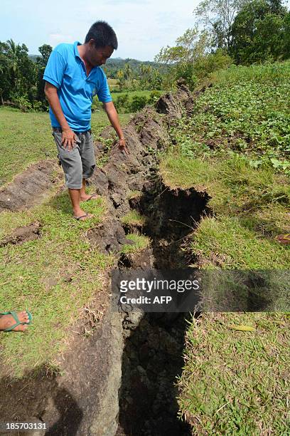 This photo taken on October 22, 2013 shows a resident standing next to a huge crack, which created a rock wall in the village of Anonang, Inabanga...