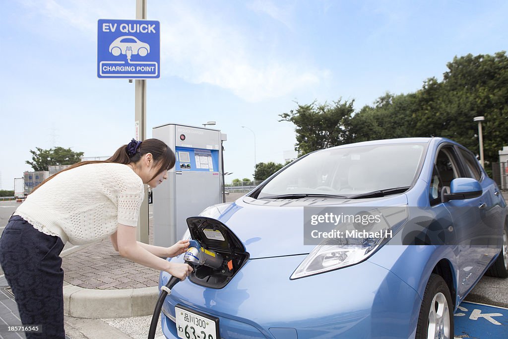 Young woman charging Electric Car