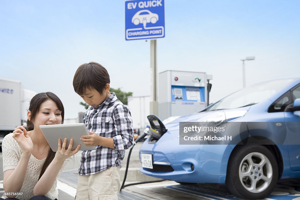 Mom and child using tablet PC while charging car