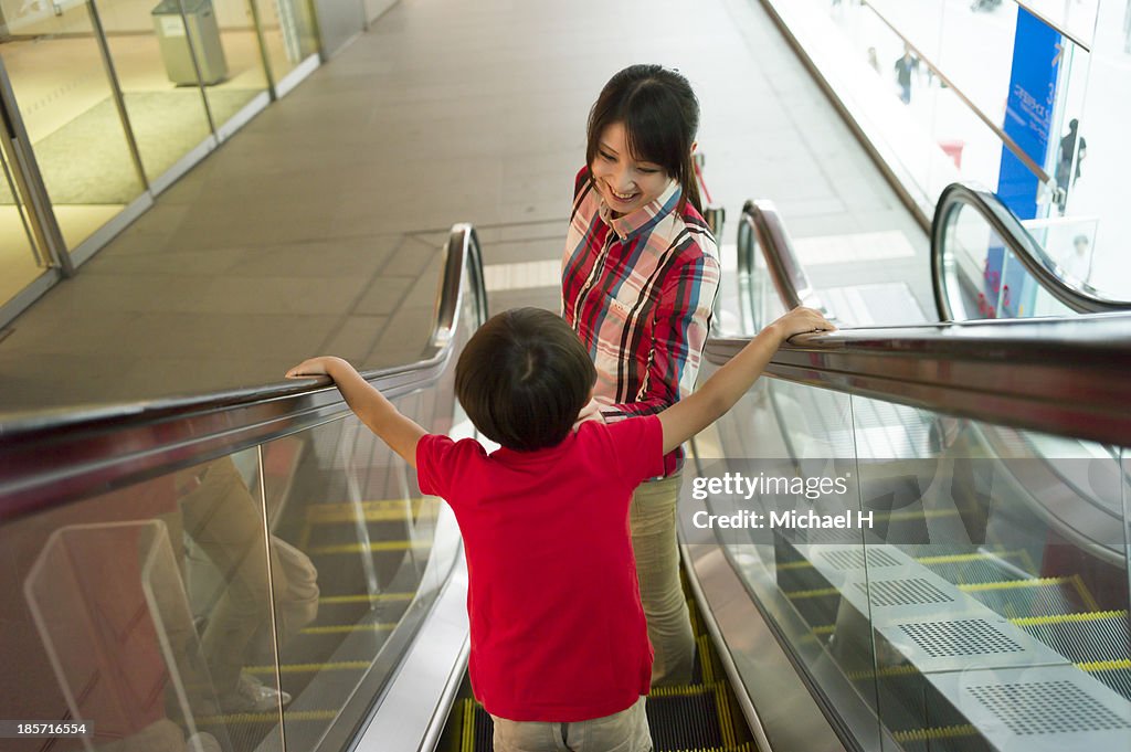 Mother and child standing on moving escalator