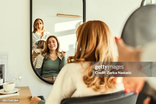 young hairdresser proudly revealing finished hairdo with mirror - highlights stockfoto's en -beelden