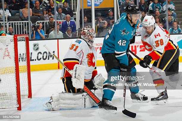 Karri Ramo and Ben Street of the Calgary Flames protect the net against Matt Pelech of the San Jose Sharks at SAP Center on October 19 2013 in San...