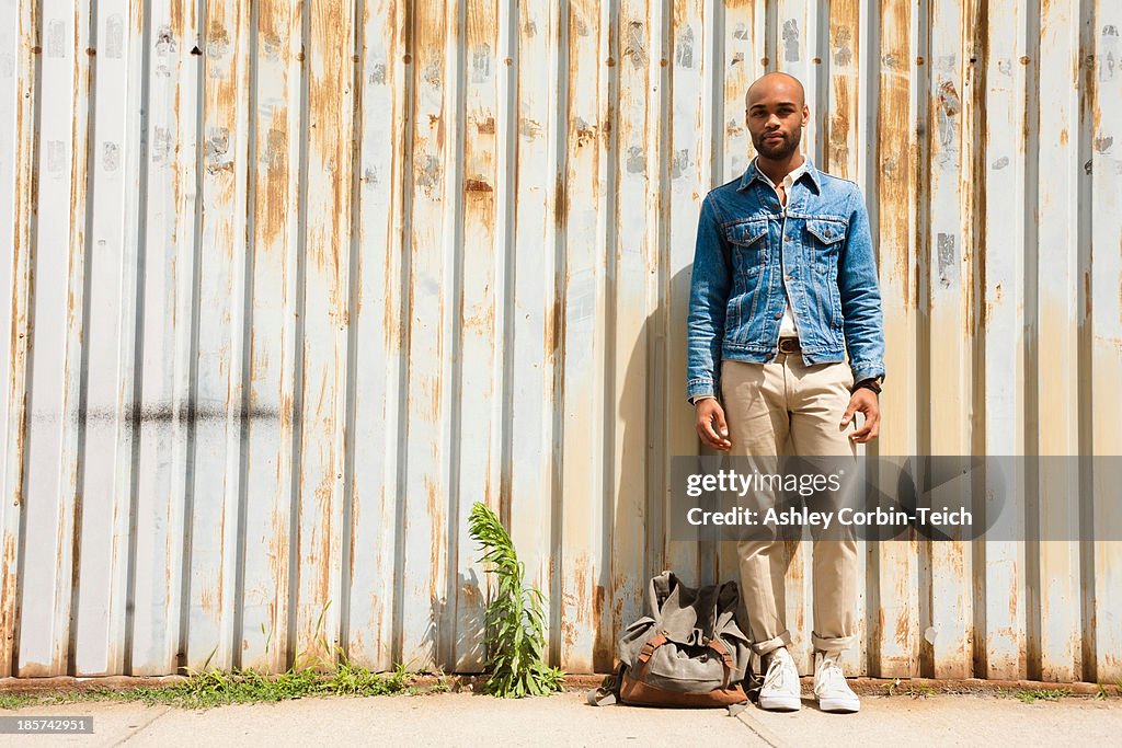 Portrait of young man in front of corrugated fence