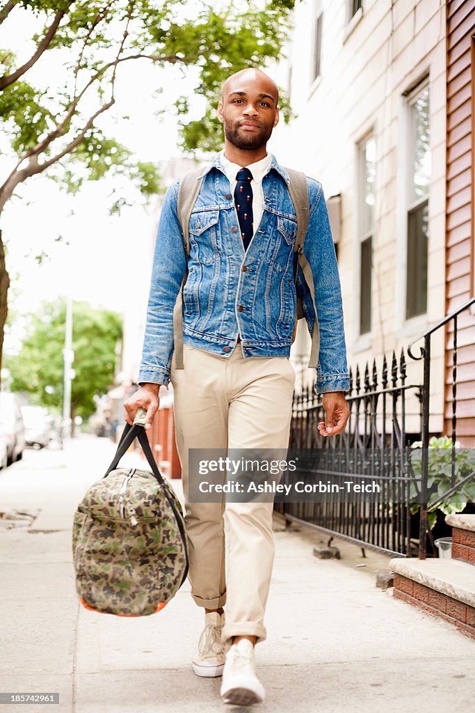 Young man walking down street with holdall