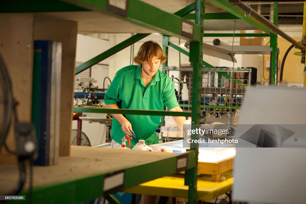 Worker preparing frame in screen printing workshop