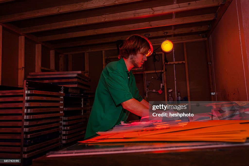 Man working in darkroom in screen printing workshop