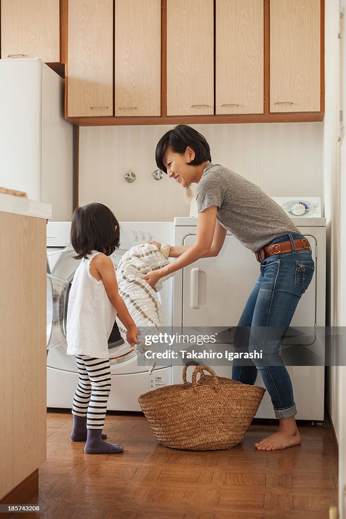 Mother and daughter putting towel into washing machine