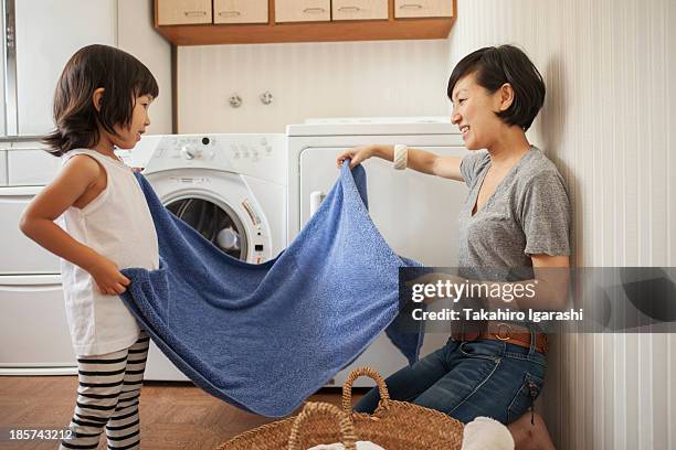 mother and daughter folding towel - domestic chores photos et images de collection