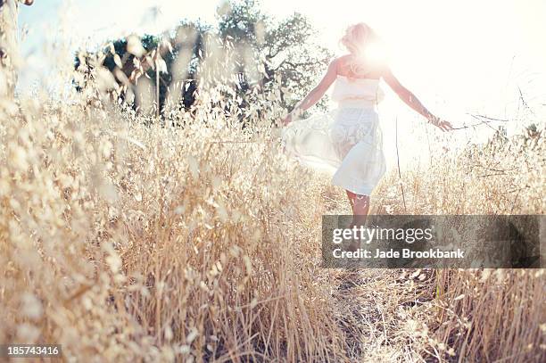 woman walking through field touching grasses - force field stock pictures, royalty-free photos & images