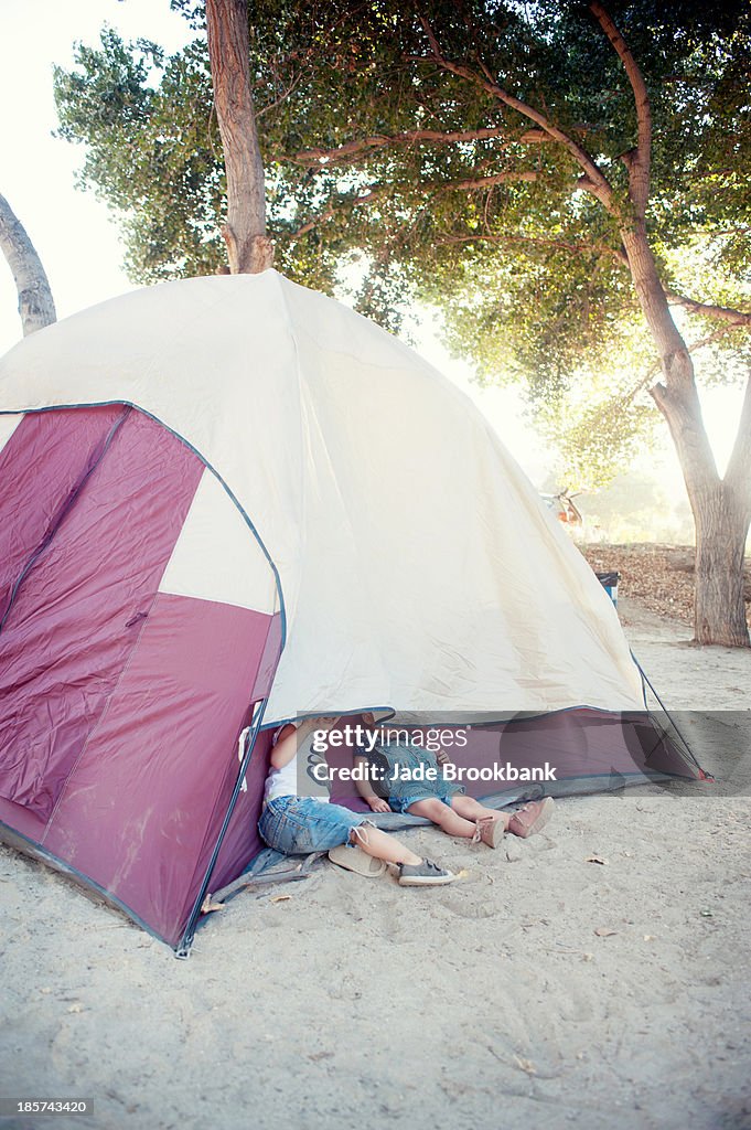 Toddler twins hiding under tent