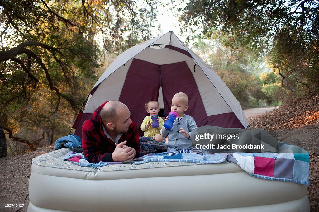 Toddler twins on camping mattress with father