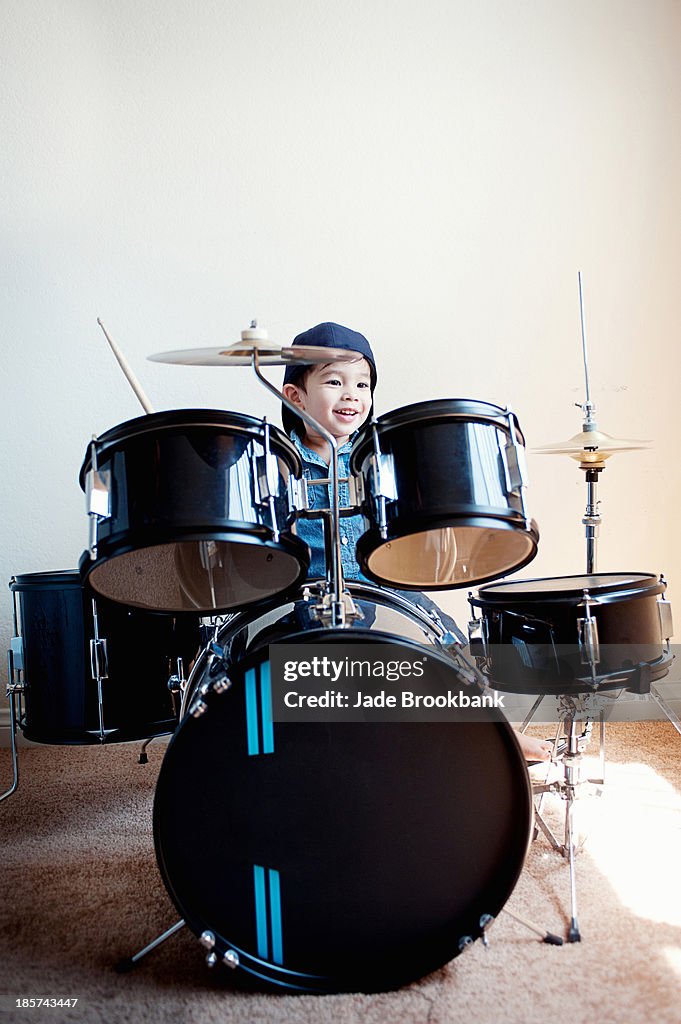 Male toddler playing on drum kit