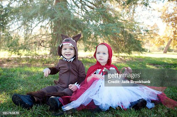 toddler twins in woods dressed up as red riding hood and wolf - red wolf fotografías e imágenes de stock