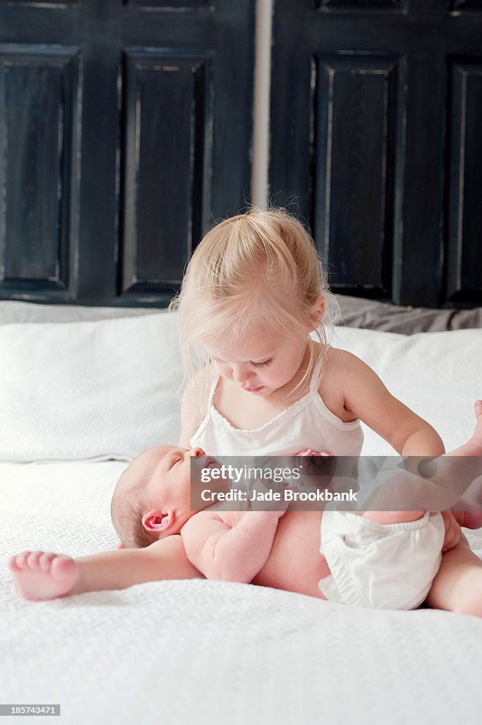 Girl sitting with baby brother on bed