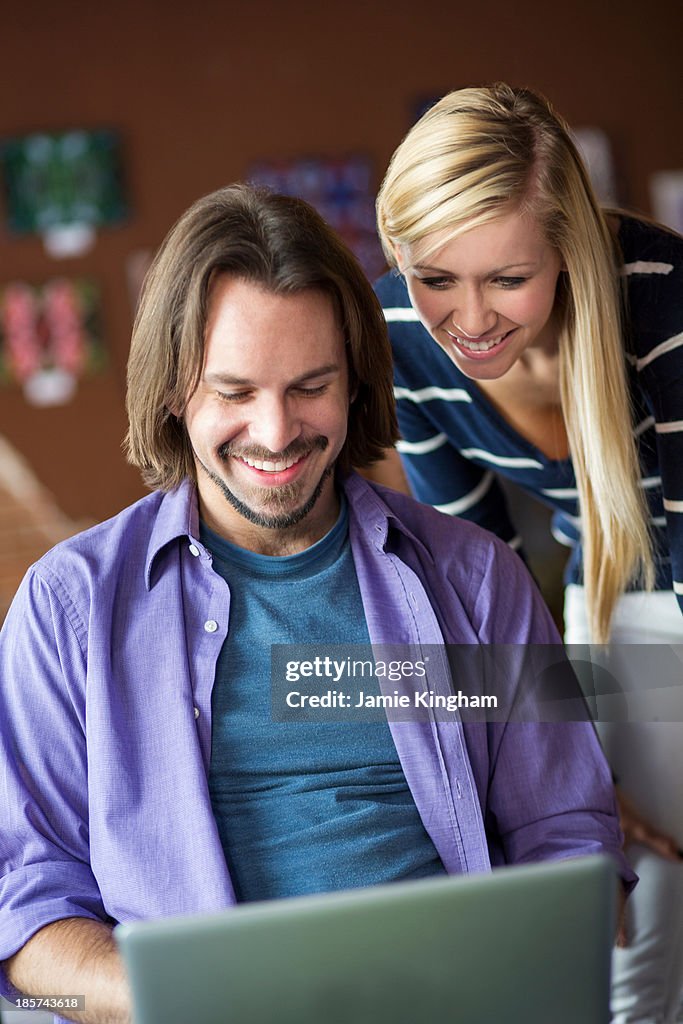 Teenage girl and mentor using at computer in cafe