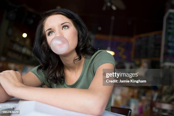 portrait of teenage girl blowing bubblegum in coffee house - bubble gum stock pictures, royalty-free photos & images