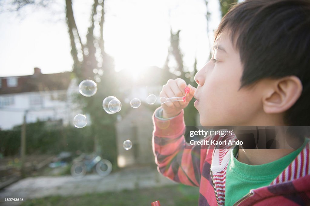 Boy blowing bubbles with wand,  close up