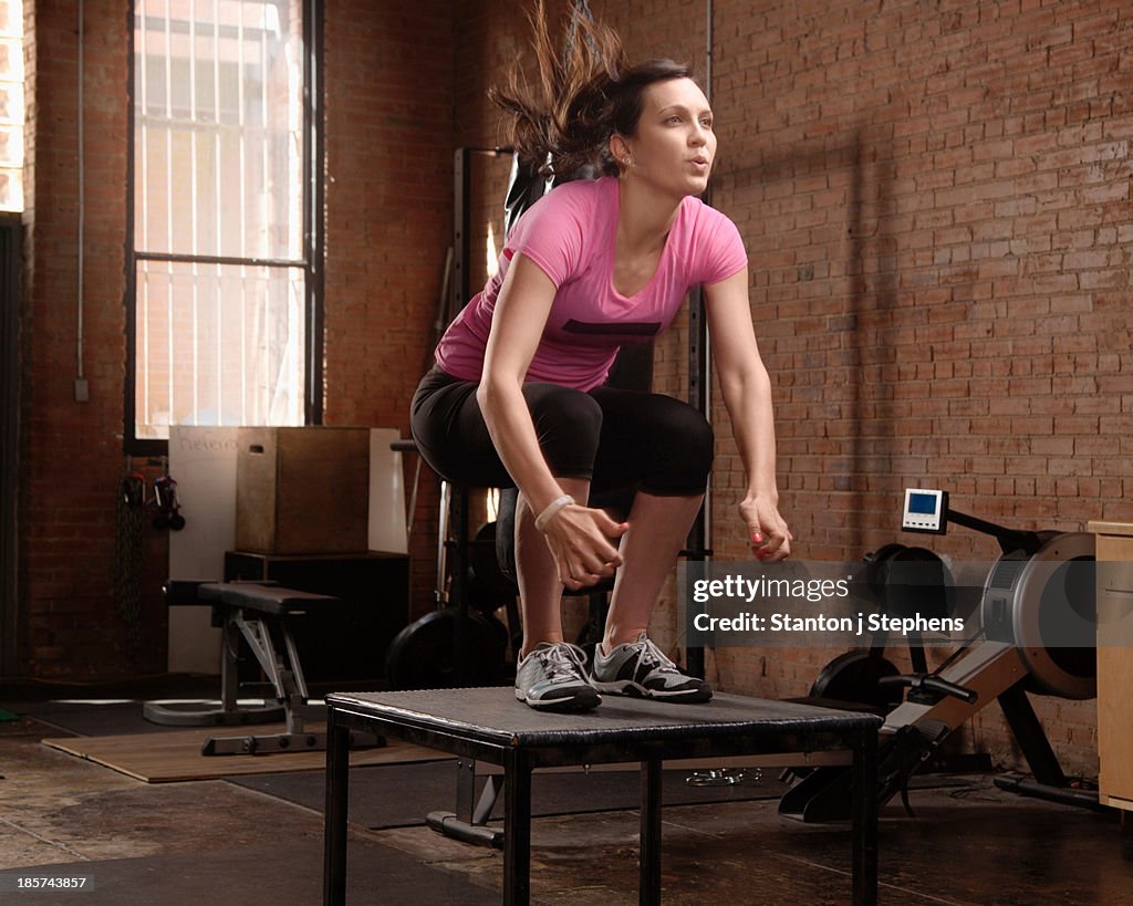 Young woman jumping on table in gym