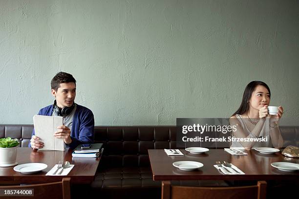 young man looking at young woman in restaurant - fremder stock-fotos und bilder