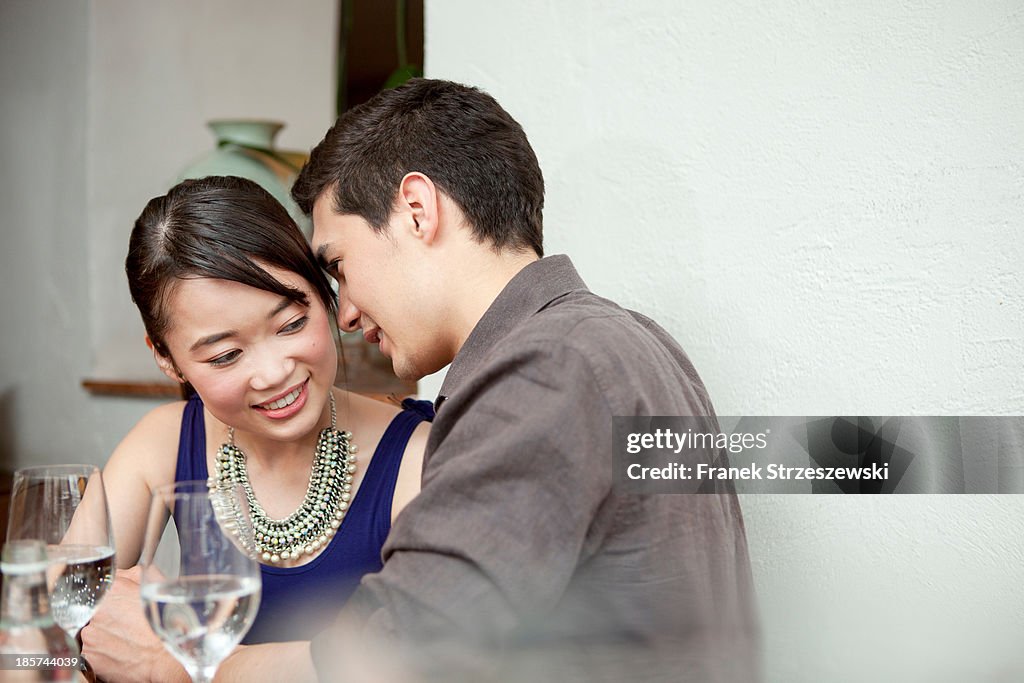 Young couple in restaurant,  man whispering