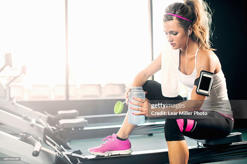 Young woman holding water bottle in gym