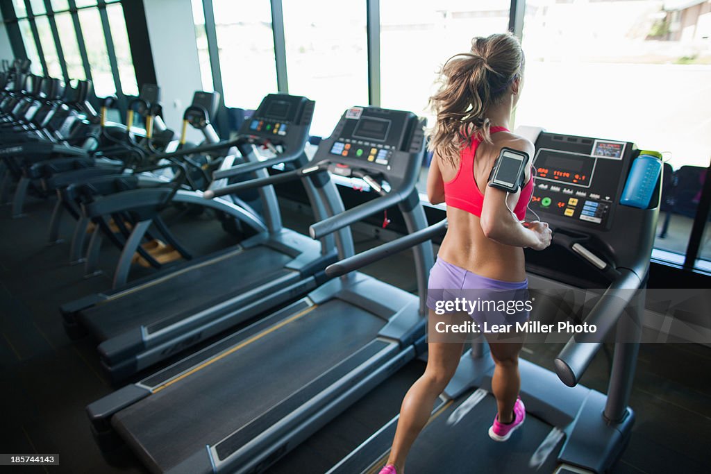 Young woman running on treadmill in gym