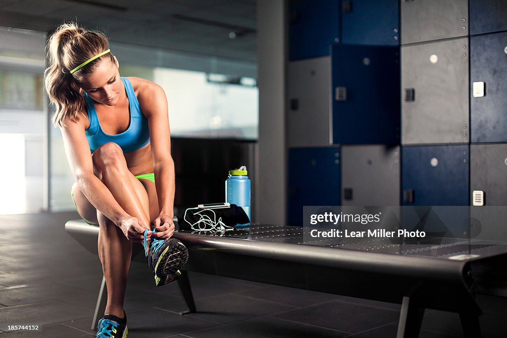 Young woman tying trainer lace in gym