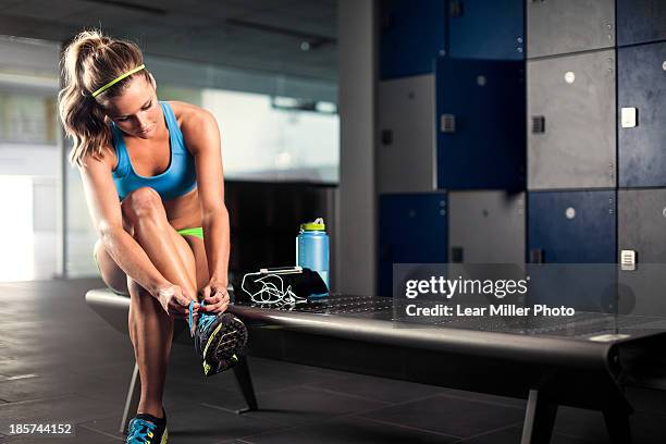 young woman tying trainer lace in gym - locker room stock pictures, royalty-free photos & images