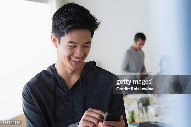 male office worker texting on mobile phone - asian young executive laughing office bildbanksfoton och bilder