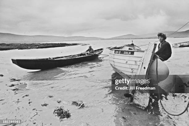 Fishermen wait at the shore in their boats, Ireland, circa 1974.