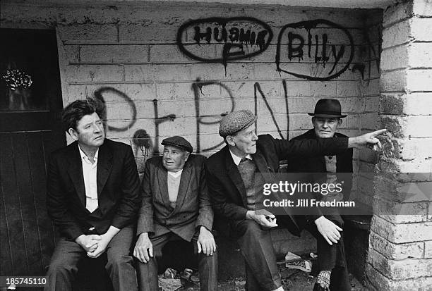 Group of men sit talking on a bench, Ireland, circa 1974.