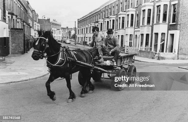 Two men riding in the street on a horse-drawn cart, London, circa 1969.