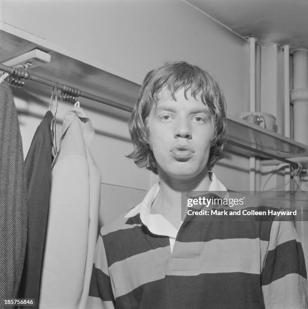 1st JANUARY: Mick Jagger from The Rolling Stones posed wearing a rugby jersey backstage on tour in Scotland in early 1964.