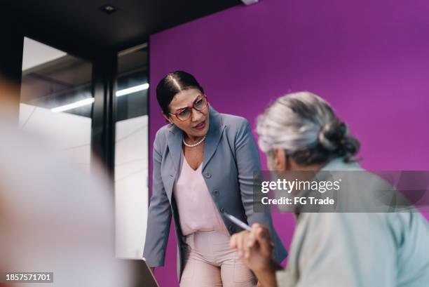 unzufriedene geschäftsfrau im gespräch mit einem kollegen während eines meetings im büro - gereiztheit stock-fotos und bilder