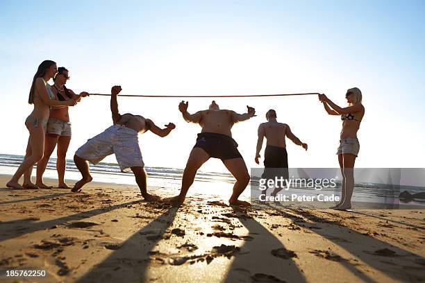 young adults on beach playing limbo - limbo stockfoto's en -beelden