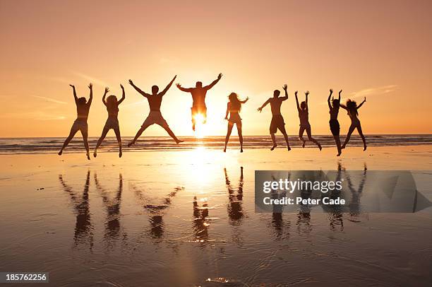 group of young adults jumping on beach at sunset - young teen girl beach ストックフォトと画像