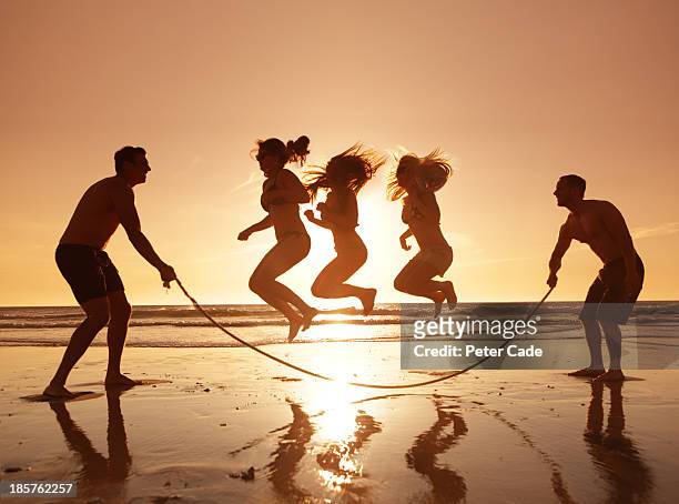 three girls jumping over skipping rope on beach - jump rope stock pictures, royalty-free photos & images